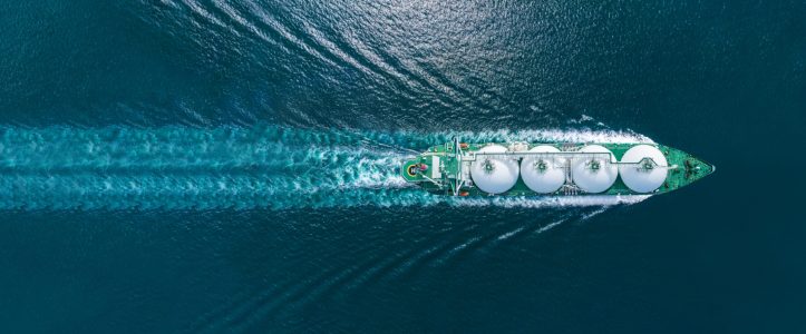 Aerial top view LNG Tanker ship (Liquified Natural Gas) with contrail in the ocean sea ship carrying container and running for export from container international port to custom ocean concept freight shipping by ship service